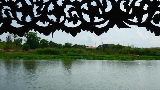 Silhouette of a wooden board that has been engraved into a beautiful pattern and a river as a background photo