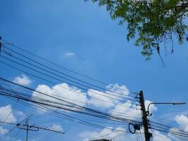 Electrical poles and cables for use in homes There is a sky and trees in the background photo