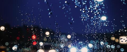 Driving in raining. Rain on car windshield or car window in rainy season and blurry traffic road in background. Rain drops on car mirror. Road in rain. Drizzle raining decreases driving visibility. photo