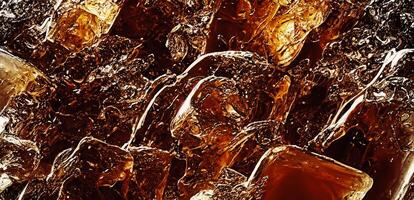 Cola with Ice. Close up of the ice cubes in cola water. Texture of carbonate drink with bubbles in glass. Cola soda and ice splashing fizzing or floating up to top of surface. Cold drink background. photo
