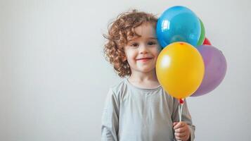 Smiling child holding a colorful balloon, standing on a white background with ample copy space, perfect for birthday and celebration themes photo