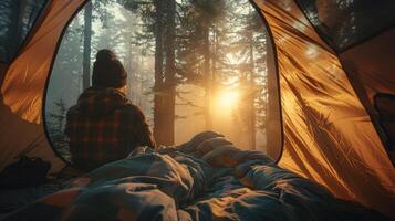 A camper waking up in a tent with morning sunlight streaming through the trees photo