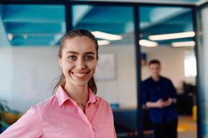 Portrait of young smiling business woman in creative open space coworking startup office. Successful businesswoman standing in office with copyspace. Coworkers working in background photo