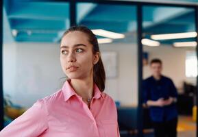Portrait of young smiling business woman in creative open space coworking startup office. Successful businesswoman standing in office with copyspace. Coworkers working in background photo