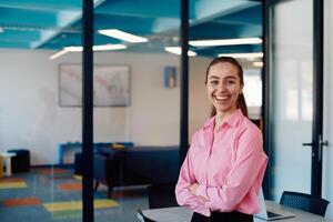 Portrait of a business woman in a creative open space coworking startup office with crossed arms. Successful businesswoman standing in office with copyspace. Associates work in the background photo
