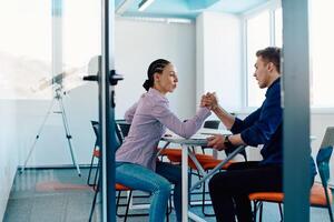In a modern startup office, a businessman and a businesswoman business colleagues engage in a symbolic arm-wrestling match, reflecting teamwork, competition, and innovation in their dynamic workplace. photo