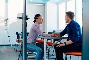 In a modern startup office, a businessman and a businesswoman business colleagues engage in a symbolic arm-wrestling match, reflecting teamwork, competition, and innovation in their dynamic workplace. photo