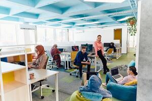 In a modern startup office, a diverse group of young and capable businesspeople engage in lively discussions about various projects, showcasing teamwork, innovation, and entrepreneurial spirit photo