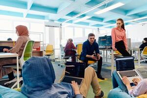 In a modern startup office, a diverse group of young and capable businesspeople engage in lively discussions about various projects, showcasing teamwork, innovation, and entrepreneurial spirit photo