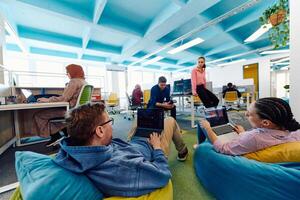 In a modern startup office, a diverse group of young and capable businesspeople engage in lively discussions about various projects, showcasing teamwork, innovation, and entrepreneurial spirit photo