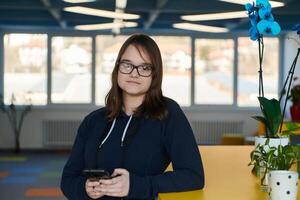 Portrait of happy multiethnic businesswoman using smartphone in agency. Successful business woman in casual clothing working in coworking creative open space office photo