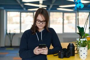 Portrait of happy multiethnic businesswoman using smartphone in agency. Successful business woman in casual clothing working in coworking creative open space office photo