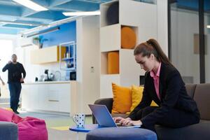 Busy businesswoman using a smartphone. Happy young businesswoman alone in a modern coworking open space office workplace. Business woman connecting with her clients in an office photo