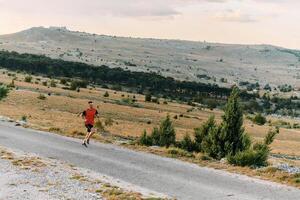 Determined Athlete Running Through Rugged Mountain Terrain at Sunrise. photo