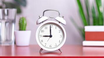 Classic white clock on a table. The clock hand points to 9 or 21 , close up photo