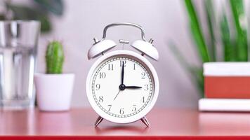 Classic white clock on a table. The clock hand points at 3, 15 close up photo