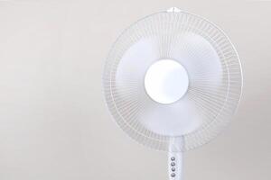 Electric Floor fan turned on white isolated on beige background. Relief from the heat, hot summer. Close up photo