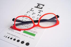 Glasses on eye testing exam chart to check eyesight accuracy of reading. photo