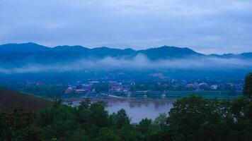 Aerial view of the mighty Mekong River winding from Chiang Khong, showing the vastness and beauty of the muddy waterway contrasting with the surrounding lush mountains and Laos villages. photo