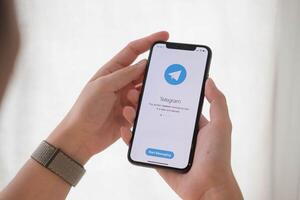 CHIANG MAI ,THAILAND JUN 21 2020 . Woman hand holding iPhone X with social networking service Telegram on the screen. iPhone 10 was created and developed by the Apple inc photo