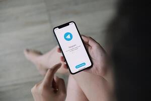 CHIANG MAI ,THAILAND JUN 21 2020 . Woman hand holding iPhone X with social networking service Telegram on the screen. iPhone 10 was created and developed by the Apple inc photo