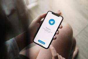 CHIANG MAI ,THAILAND JUN 21 2020 . Woman hand holding iPhone X with social networking service Telegram on the screen. iPhone 10 was created and developed by the Apple inc photo