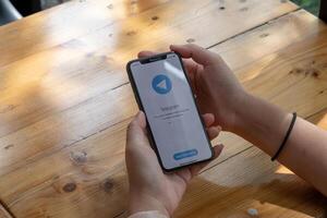 CHIANG MAI, THAILAND, JUL 27, 2021 . Woman hand holding iPhone X with social networking service Telegram on the screen. iPhone 10 was created and developed by the Apple inc photo