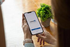 CHIANG MAI, THAILAND, OCT 17, 2021 . A women holds Apple iPhone pro max with LinkedIn application on the screen.LinkedIn is a photo-sharing app for smartphones photo