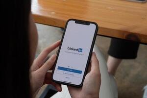 CHIANG MAI, THAILAND, OCT 10, 2021 . A women holds Apple iPhone 12 with LinkedIn application on the screen.LinkedIn is a photo-sharing app for smartphones photo