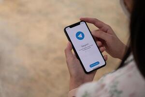 CHIANG MAI, THAILAND, NOV 14, 2021 . Woman hand holding iPhone X with social networking service Telegram on the screen. iPhone 10 was created and developed by the Apple inc photo