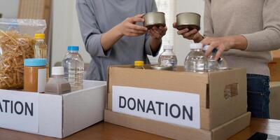 Group of volunteer woman working in home. Happy volunteer looking at food donation box separating donations stuffs photo