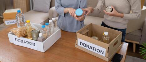 Group of volunteer woman working in home. Happy volunteer looking at food donation box separating donations stuffs photo