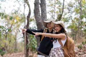 Cheerful romantic lesbian couple traveler with backpack on their backs go hiking through the forest in the mountains in summer photo
