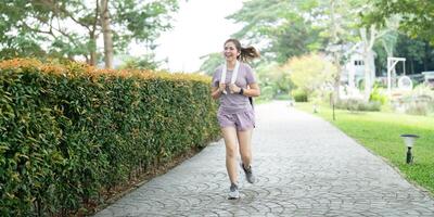 Asian fitness female sportswoman runner doing morning jogging exercise training outdoor. Happy smile woman asian running in the park photo