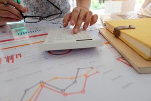 Close up of businessman or accountant hand holding pencil working on calculator to calculate financial data report, photo