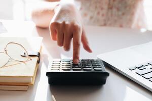 Close up Businesswoman using calculator and laptop for do math finance on wooden desk in office photo