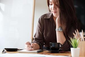 Attractive accountant counting on calculator, making notes some data on notepad photo