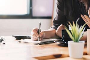 accountant counting on calculator, making notes some data on notepad photo