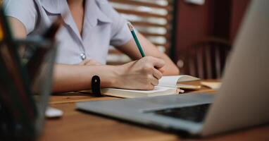 Close up student study online with teacher, young woman learn language listen lecture watch webinar write notes photo