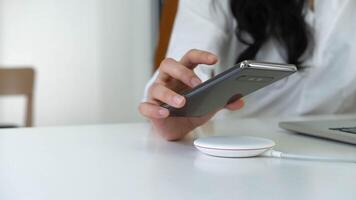 Working Woman putting smartphone on wireless charger in office photo