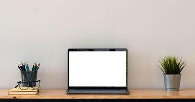 Cropped shot of simple workspace with blank screen laptop, cup, stationery and copy space photo