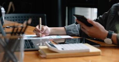 Businessman pen pointing turnover with graph chart report and use laptop computer for analysis data photo