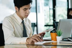 businessman or accountant hand holding pencil working on calculator to calculate financial data report, accountancy document and laptop computer at office, business concept photo