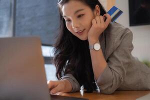 Asian woman makes a purchase on the Internet on the laptop computer with credit card photo