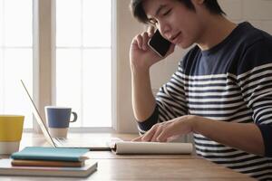 Happy young man learn language listen lecture watch webinar write notes look at laptop sit in home, distant education photo