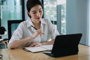 Woman using smart tablet for training online and writing lecture note. e-learning education concept photo