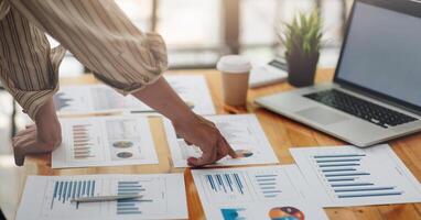 Businessman discussing analysis charts or graphs on desk table and using laptop computer.Close up male analysis and strategy concept. photo