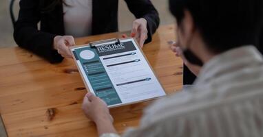 job interview in office, focus on resume writing tips, employer reviewing good cv of prepared skilled applicant, recruiter considering application, hr manager making hiring decision. photo