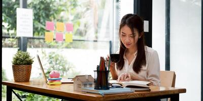 Shot of asian woman real estate agent working with laptop computer in her office. photo
