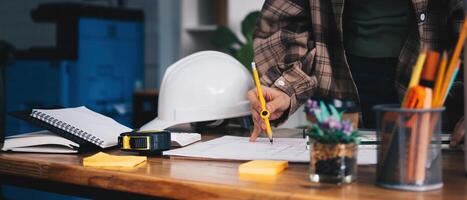 Cropped woman architect design working drawing sketch plans blueprints and making architectural construction model in architect studio. photo